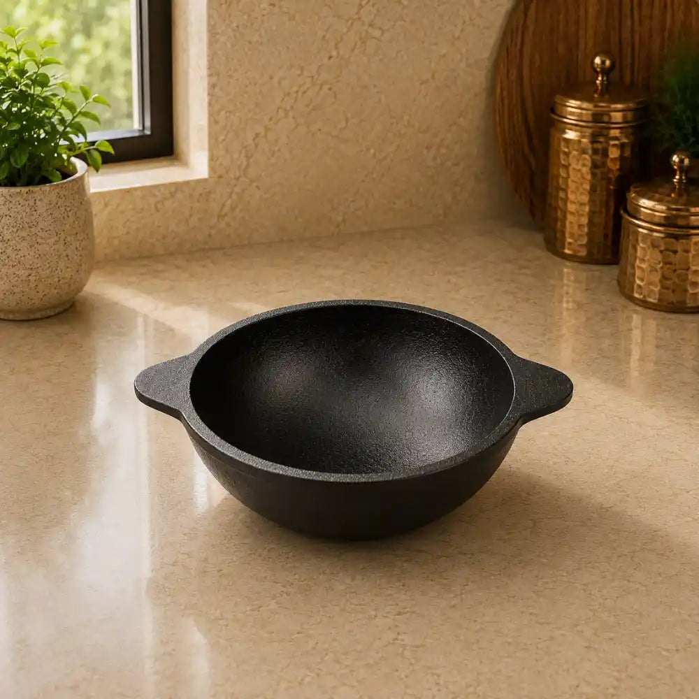Black cast iron bowl on a beige countertop with decorative items in the background