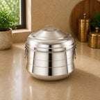 Stainless steel serving dish on a countertop with decorative elements in the background