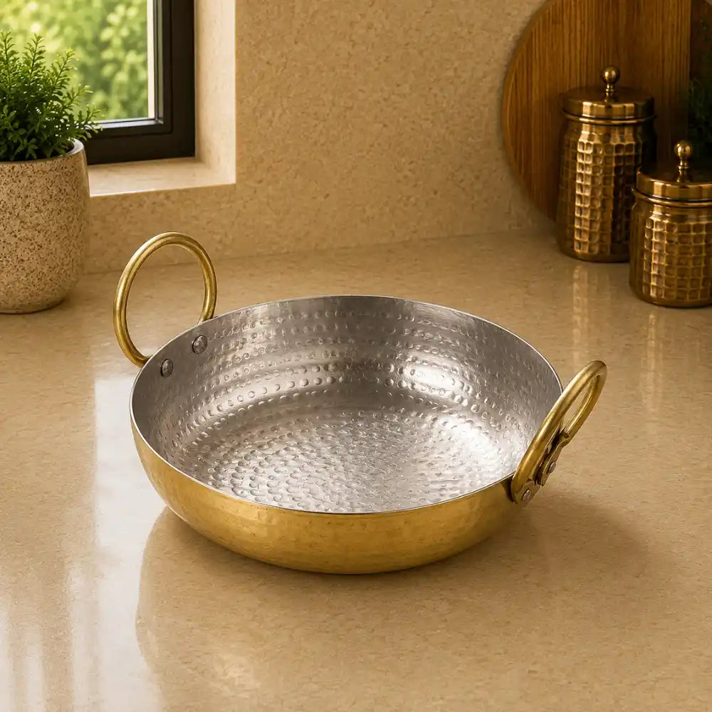 Hammered metal pan with gold handles on a beige surface