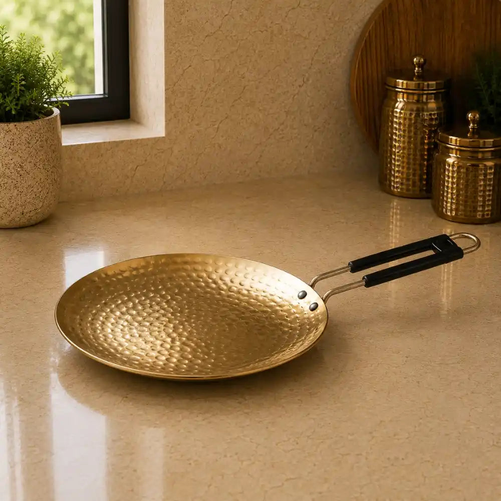 Gold frying pan with black handle on a beige countertop