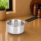 Stainless steel saucepan with black handle on a beige surface