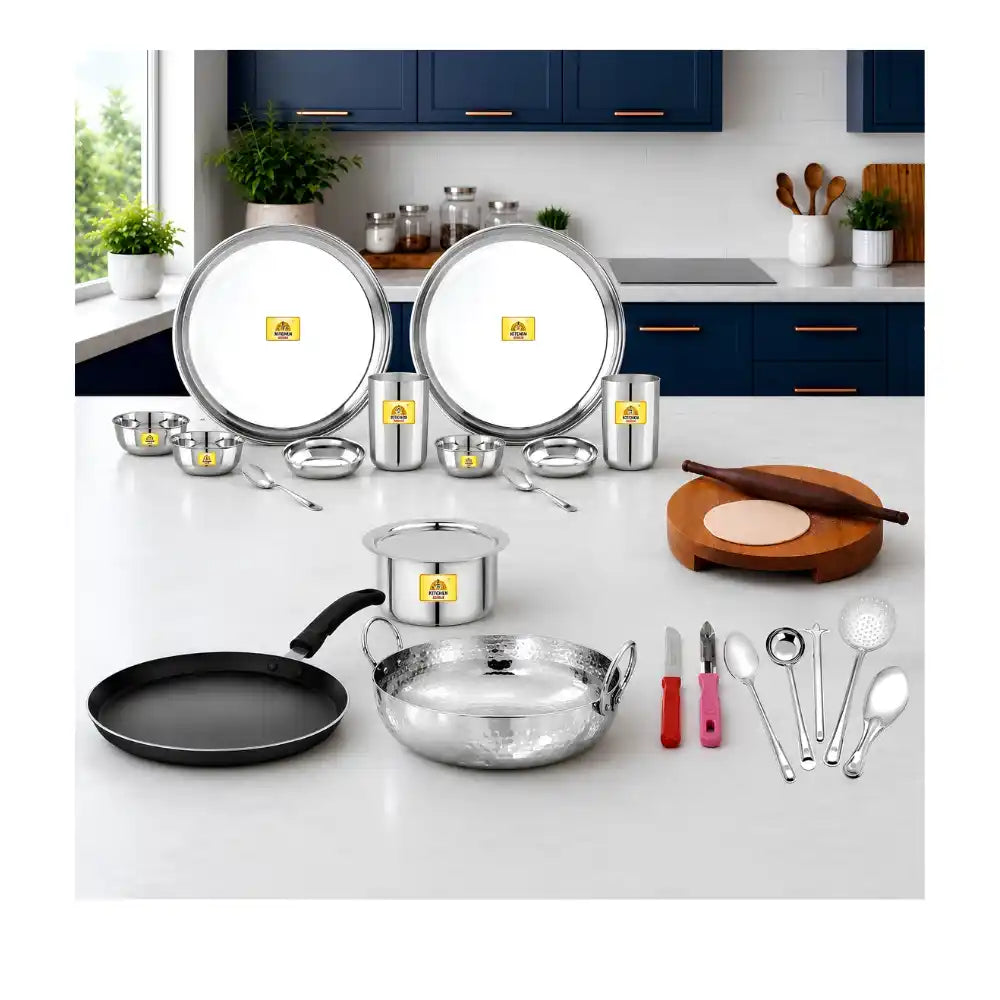 Set of stainless steel cookware and kitchen utensils on a white countertop with a kitchen background.