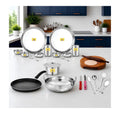 Set of stainless steel cookware and kitchen utensils on a white countertop with a kitchen background.