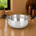 Stainless steel pot with black handles on a reflective surface