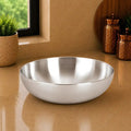 Silver bowl on a reflective surface with a neutral background