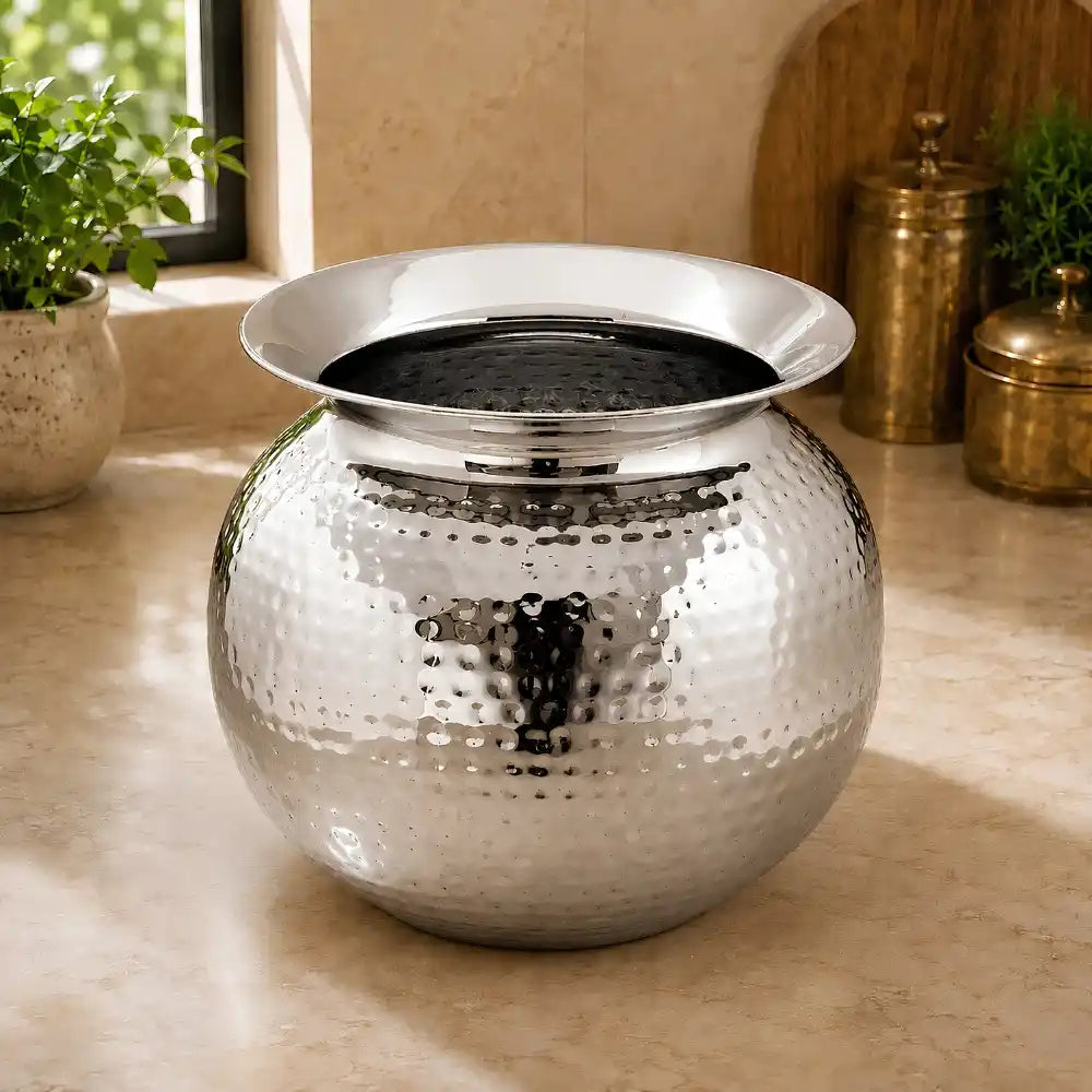 Silver decorative pot on a surface with plants in the background