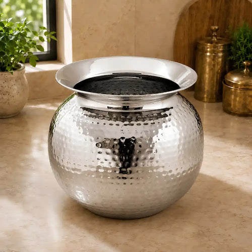 Silver decorative pot on a surface with plants in the background