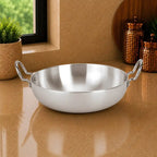 Stainless steel wok on a reflective surface with a neutral background