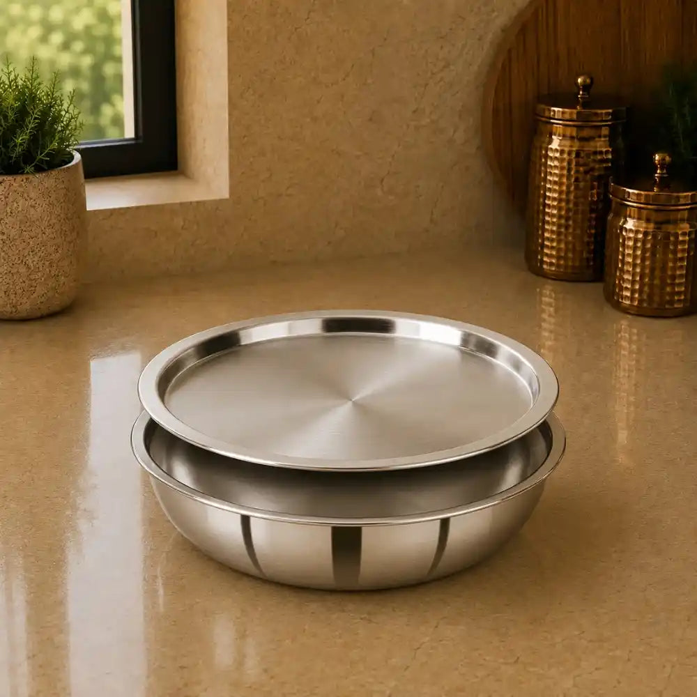 Two stainless steel trays on a beige surface with decorative jars and plants in the background.