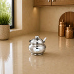 Silver sugar bowl with a spoon on a beige kitchen counter