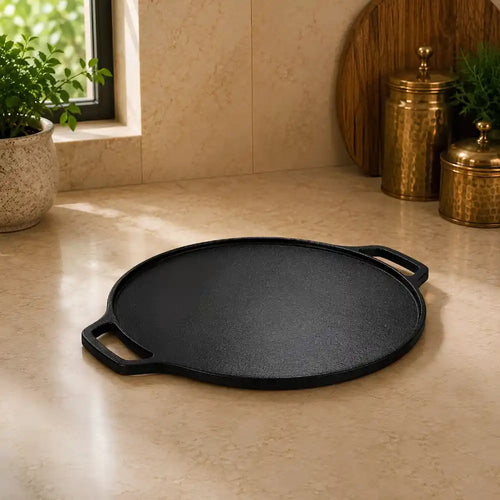 Black cast iron griddle on a beige countertop with decorative items in the background