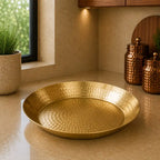 Gold decorative plate on a beige surface with a window and plants in the background
