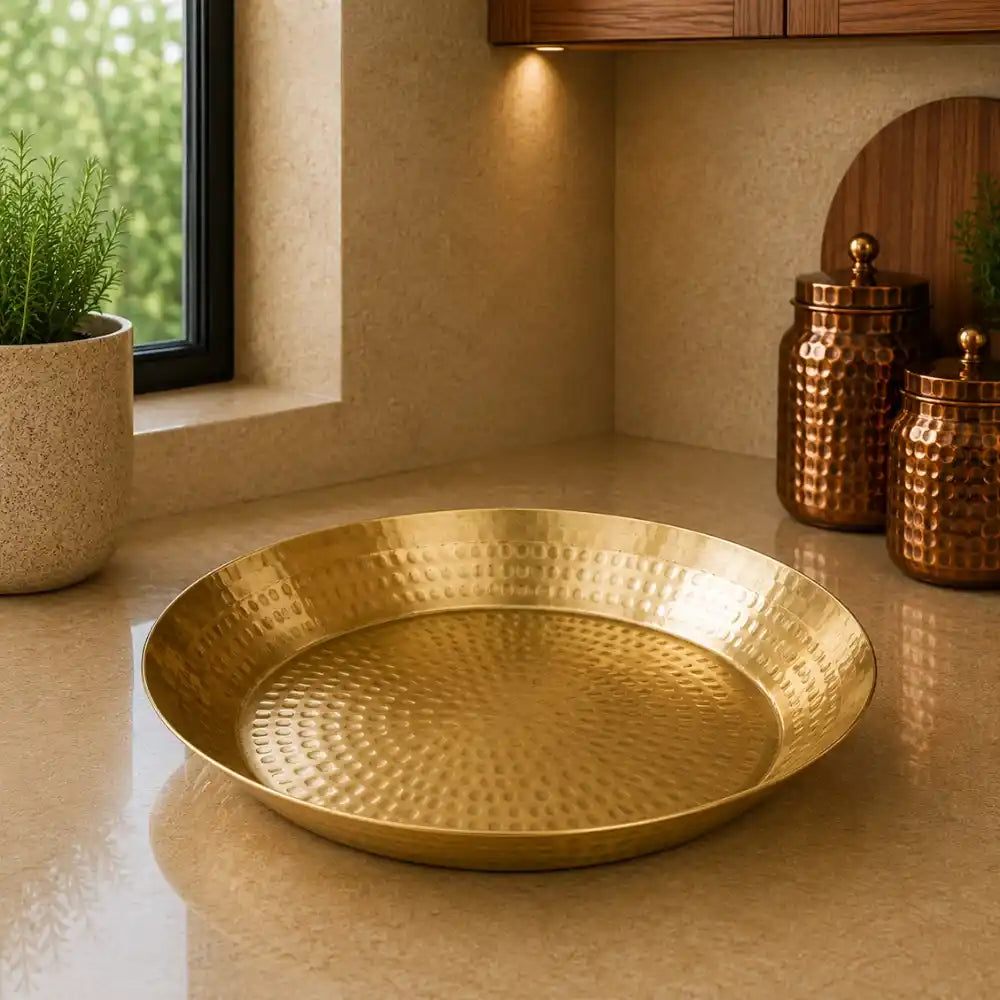 Gold decorative plate on a beige surface with a window and plants in the background