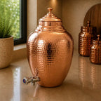 Copper dispenser jug with a plant and mirror in the background