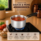 Stainless steel saucepan on a stove with tomato sauce, surrounded by kitchen items.
