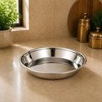 Silver metal bowl on a beige countertop with decorative items in the background