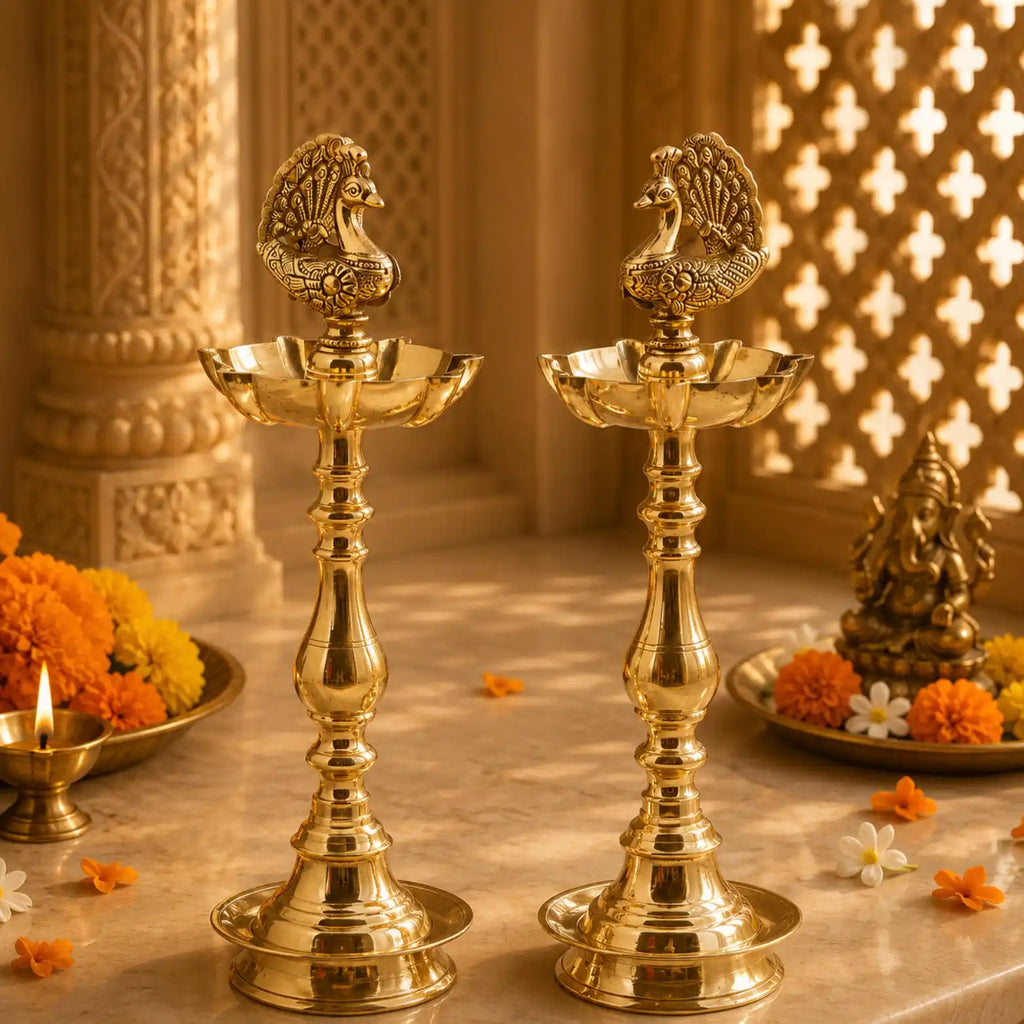 Two ornate brass oil lamps with peacock finials on a marble surface, surrounded by marigold flowers and a decorative background with warm lighting.