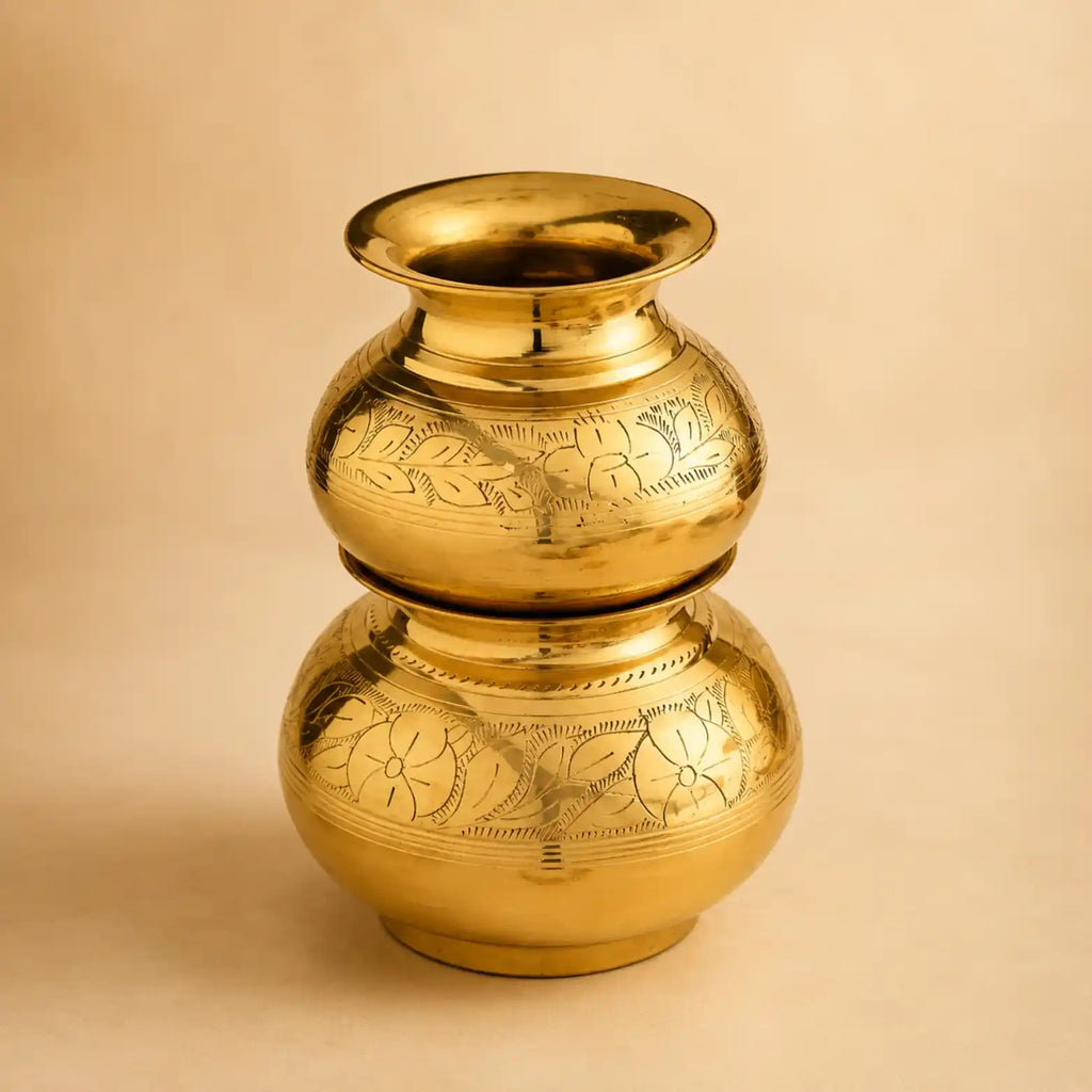 A polished brass double-bulb vase with engraved floral patterns, set against a solid beige background.