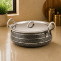 Speckled cookware with silver lid on a beige surface