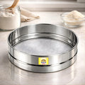Stainless steel fine mesh chalni (flour sieve) on a modern kitchen countertop, ideal for sifting atta, maida, besan, powdered sugar, and spices.