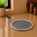 Round metal strainer with handle on a reflective surface