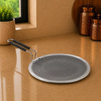 Round metal strainer with handle on a reflective surface