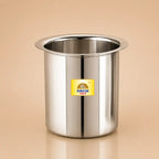 A stainless steel cylindrical cup or tumbler with a flared rim, featuring a yellow and blue BAKESH GOLD logo sticker on the front, set against a warm beige background.