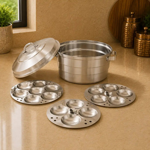Set of silver cookware including a large pot, lid, and three smaller round trays on a beige surface.