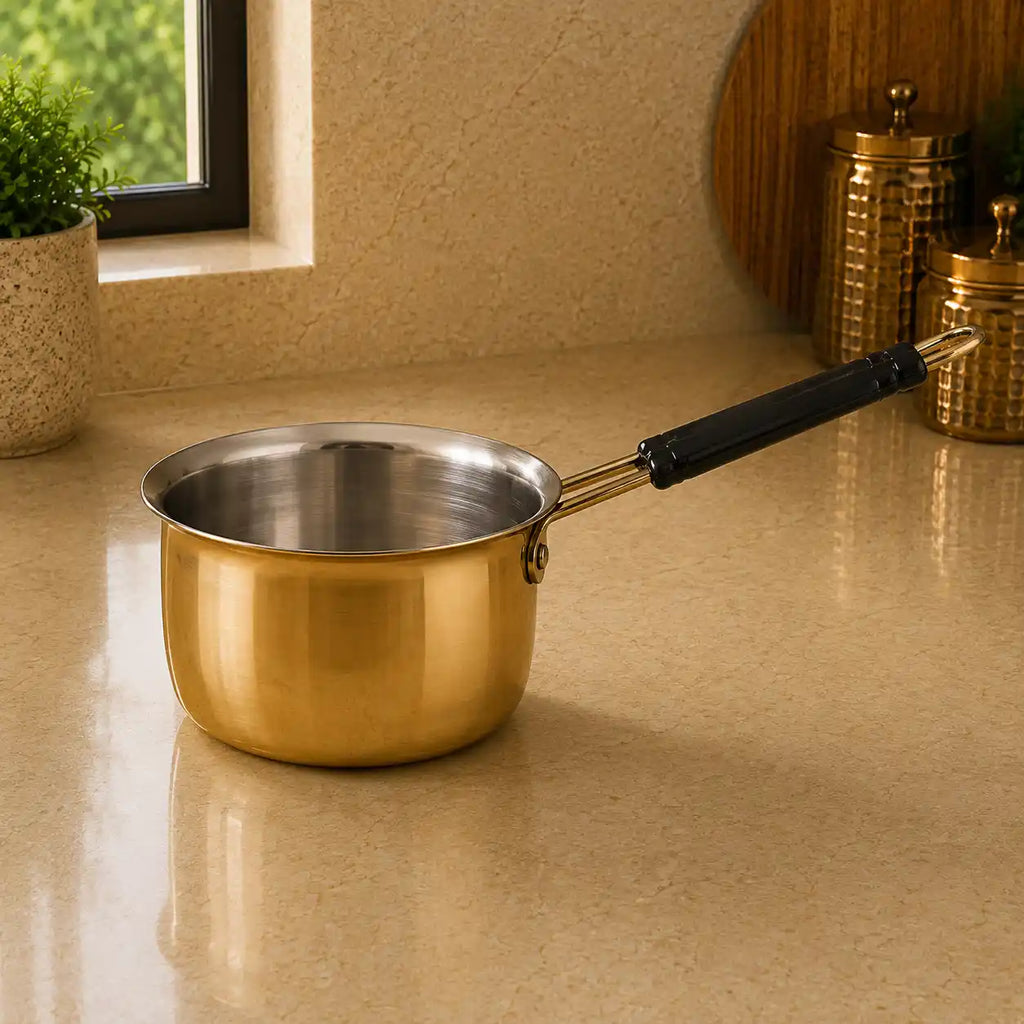 Gold saucepan with black handle on a beige countertop