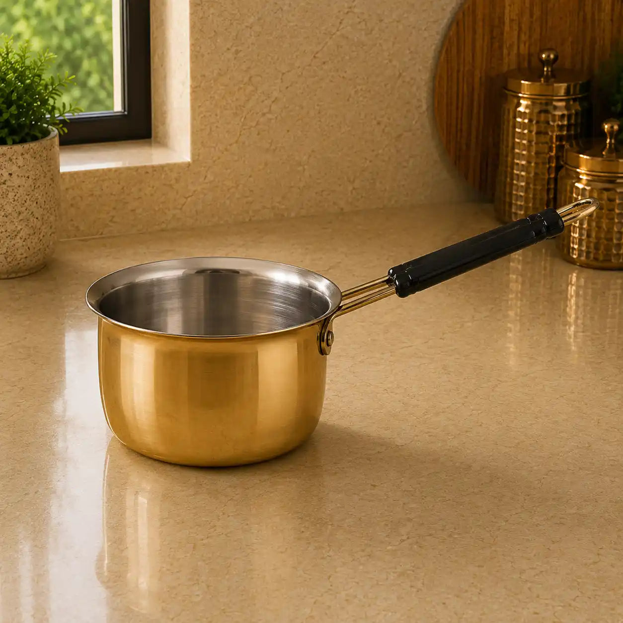 Gold saucepan with black handle on a beige countertop