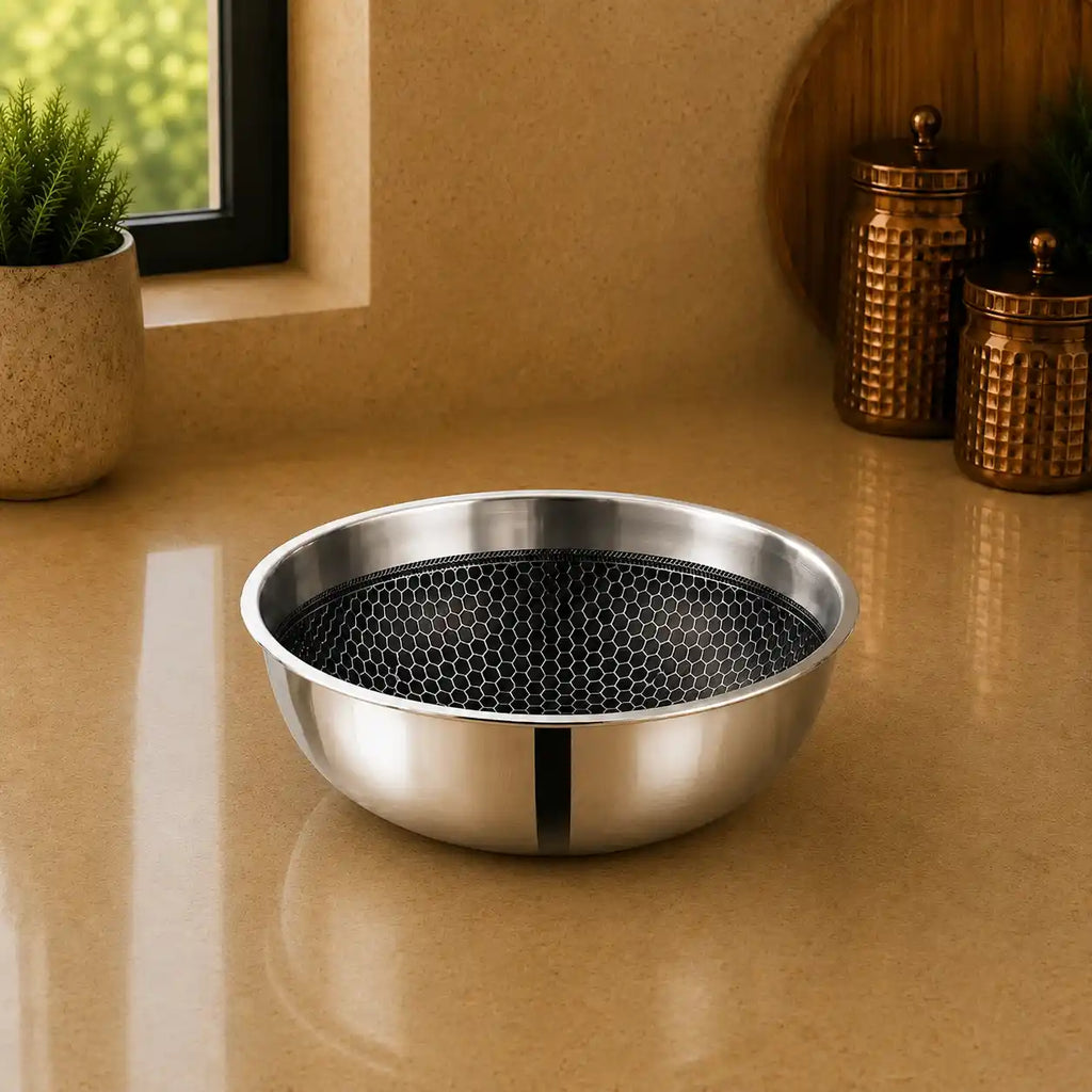 A stainless steel bowl with a black honeycomb-patterned insert, placed on a beige countertop in a kitchen setting.