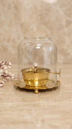 Brass incense burner inside a glass dome on a wooden surface with a blurred background