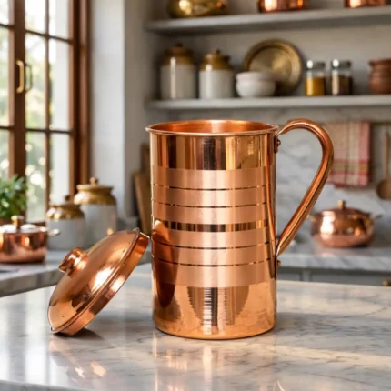 Polished copper water jug with lid and handle placed on marble kitchen countertop