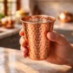 Hammered copper drinking glass placed on marble kitchen countertop